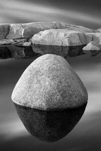 Black and white photography of rocks floating in water by iCanvas artist Jeff Friesen