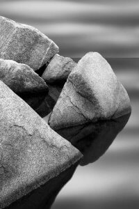 Black and white nature photography of granite stones above water by iCanvas artist Jeff Friesen