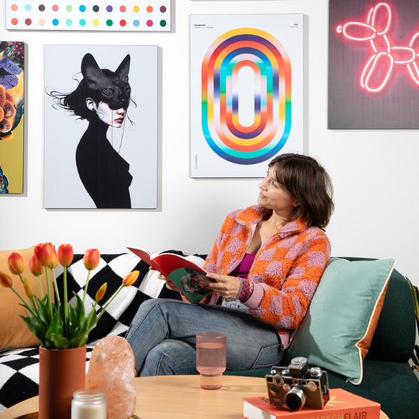 woman reading a book looking up at her gallery wall of metal art